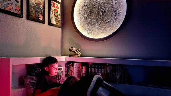 Child reading a book under a large moon lamp in a cozy room.